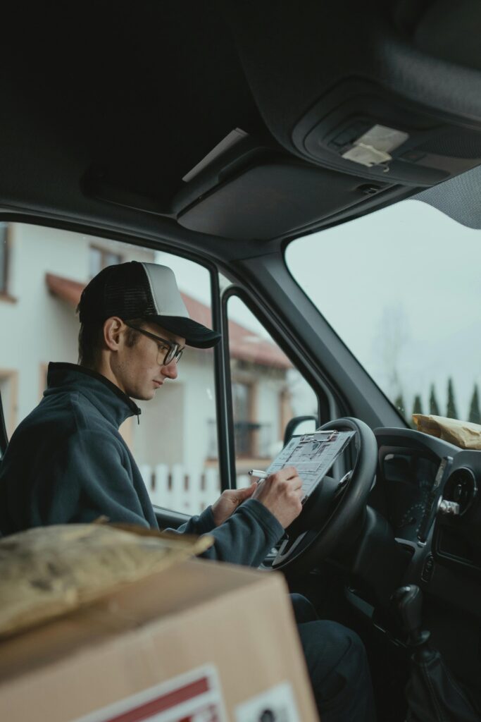 Delivery driver checks clipboard in van, preparing packages for delivery.